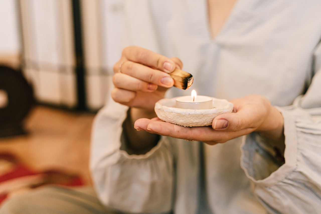 A calming scene of one holding a candle and lighting incense for relaxation and mindfulness.